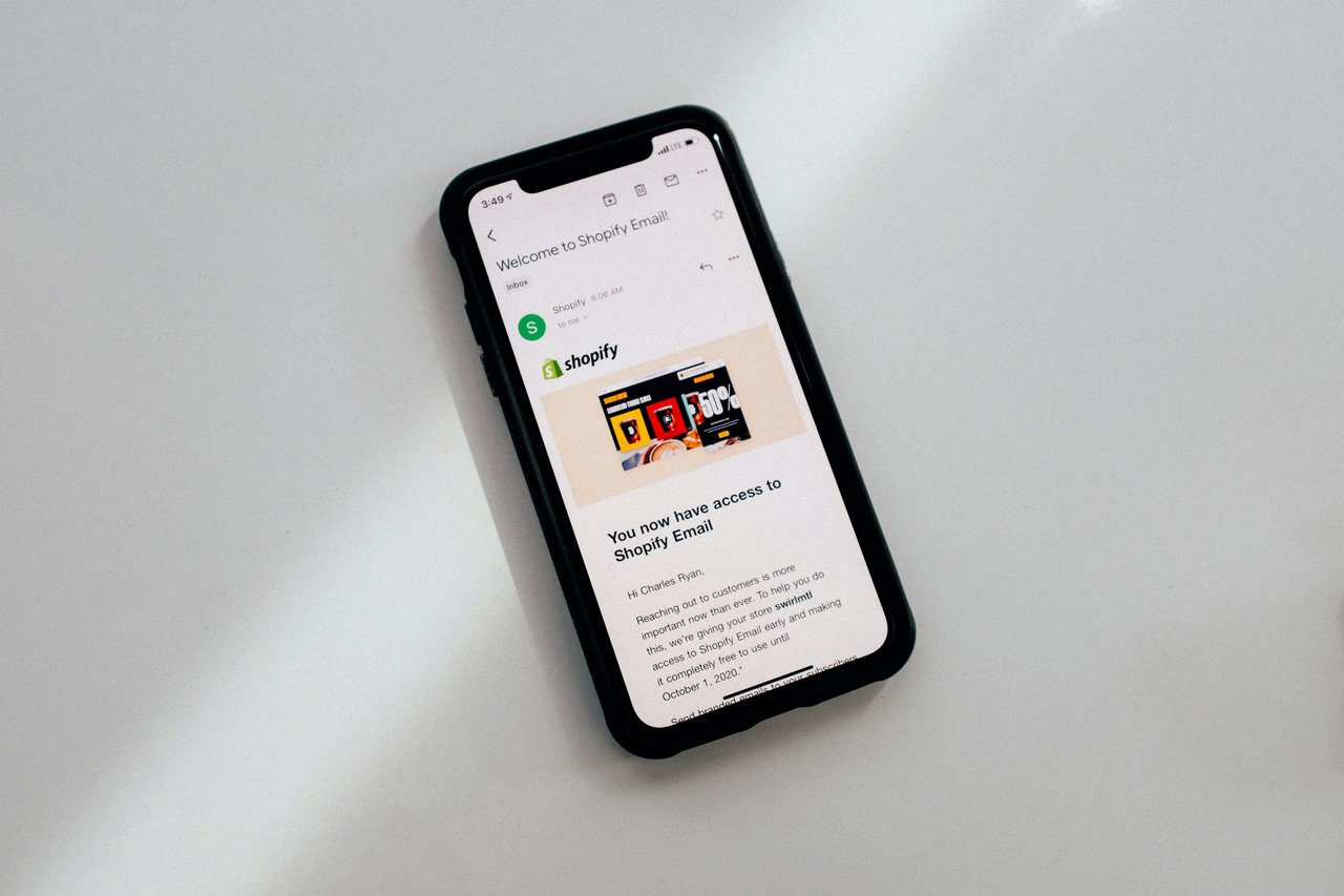 A phone showing an email that says 'Welcome to Shopify Email'